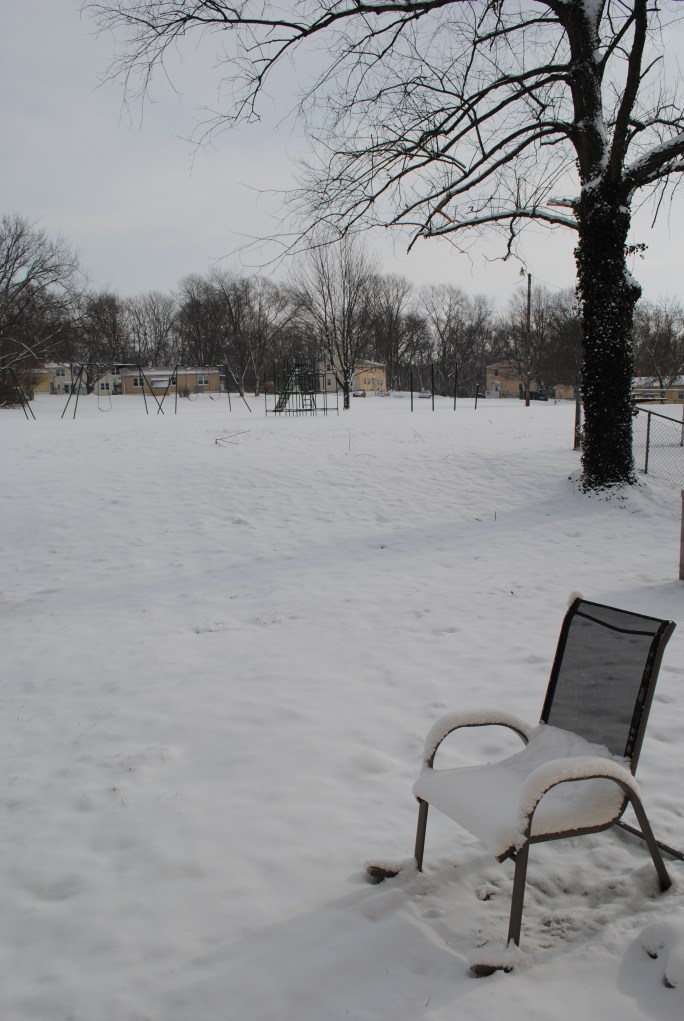 view of snow coved yard, lawn chair, and play ground equiptment
